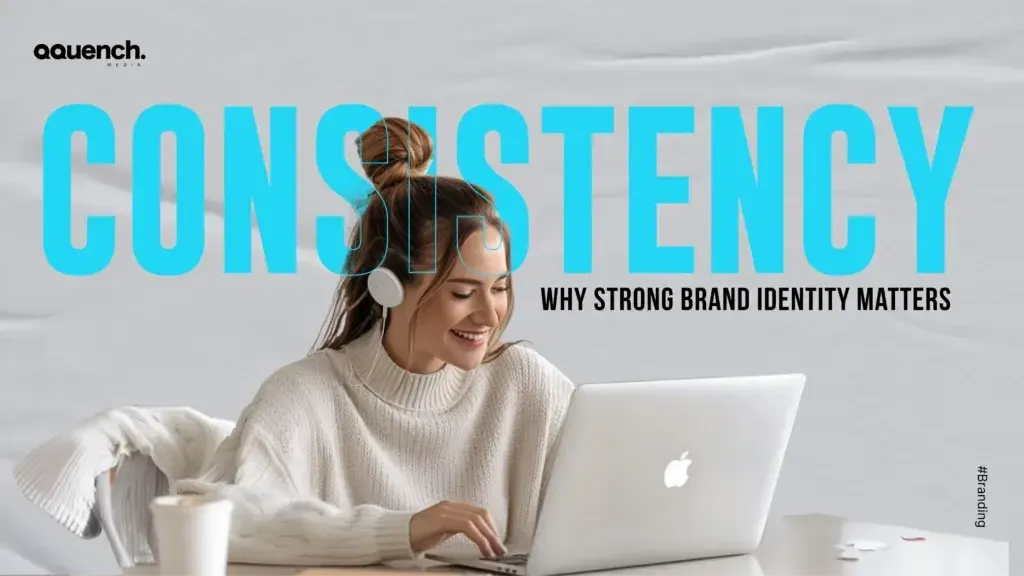 Woman in cozy sweater smiling while working on a laptop with the word “CONSISTENCY” in bold blue letters — highlighting the importance of strong brand identity.