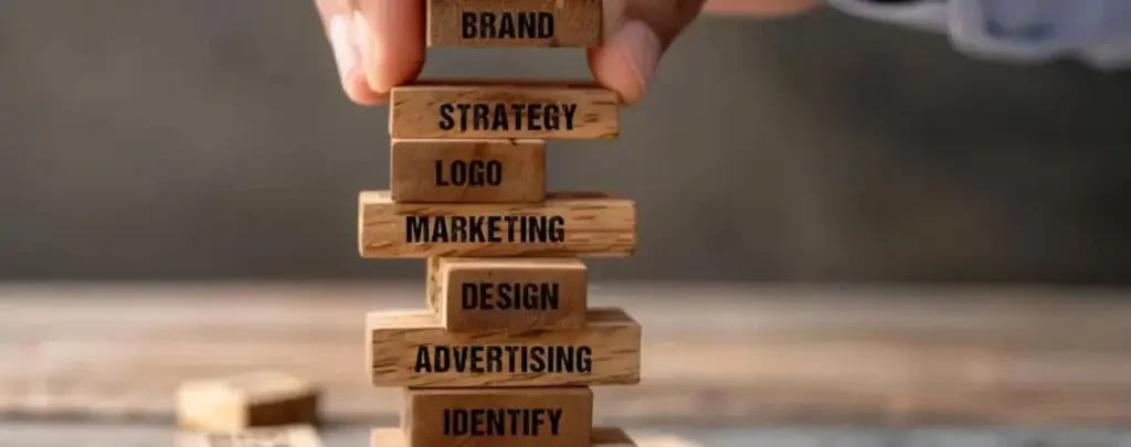 Stacked wooden blocks labeled with terms like 'Brand,' 'Strategy,' 'Logo,' and 'Marketing